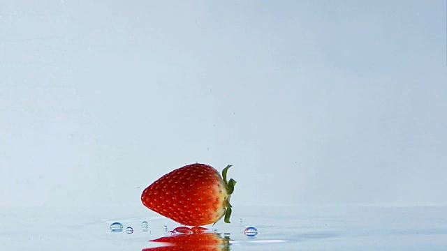 草莓落下和在水上滚动的慢镜头。视频下载