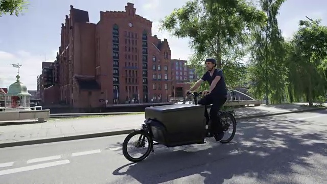 帅气的货运自行车快递正在大街上骑车视频素材