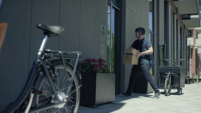 帅气的快递员用他的货运自行车给客户送包裹视频素材