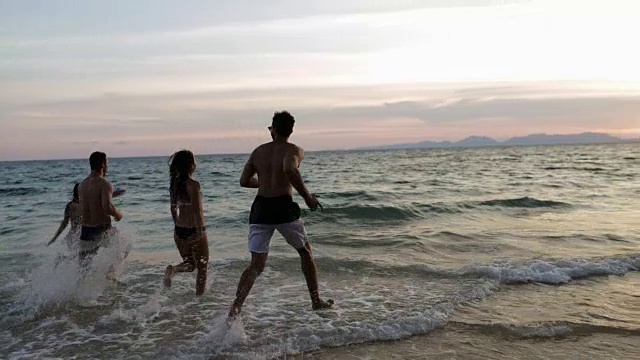 一群人在日落的海滩上在海上跑步溅起水花混合赛跑愉快的朋友在度假视频素材