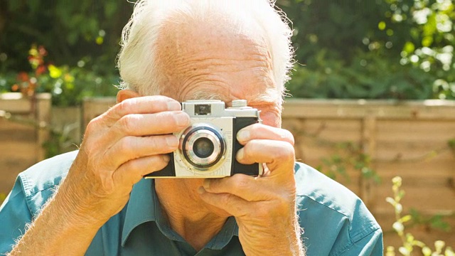 一位老人正在用一台旧相机拍照视频下载