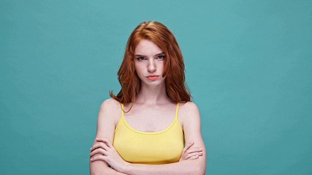 愤怒的红发女孩双手交叉站在蓝色背景下说不孤立视频素材