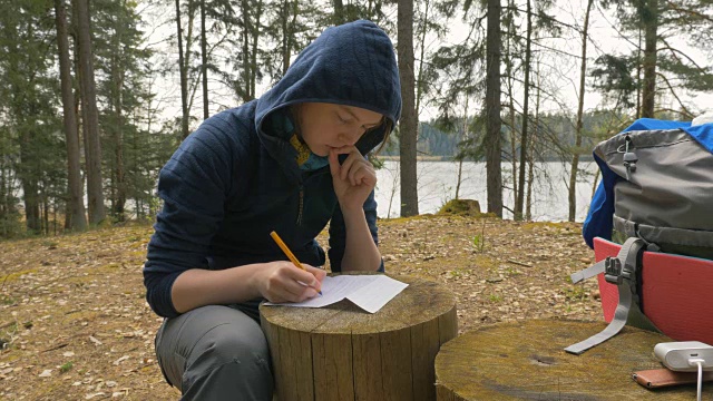 女孩正在森林里的树桩上写纸条视频下载