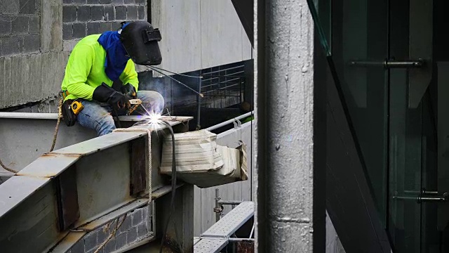 在建筑工地的钢框架结构上工作的焊工穿着整体和安全设备视频素材