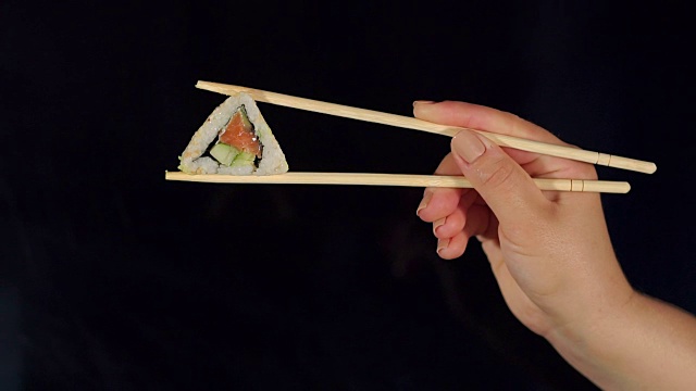 黑暗中用筷子夹寿司的女人。视频素材