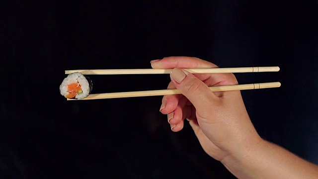 黑暗中用筷子夹着寿司的女人。视频素材