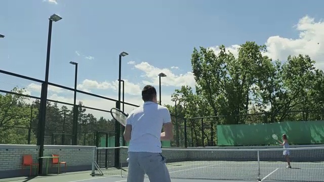 两个年轻的朋友在室外的网球场上打网球视频素材