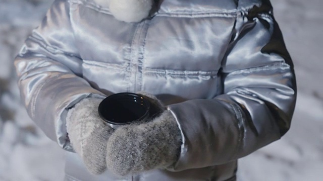 戴手套的小女孩在雪地上拿着茶杯视频下载