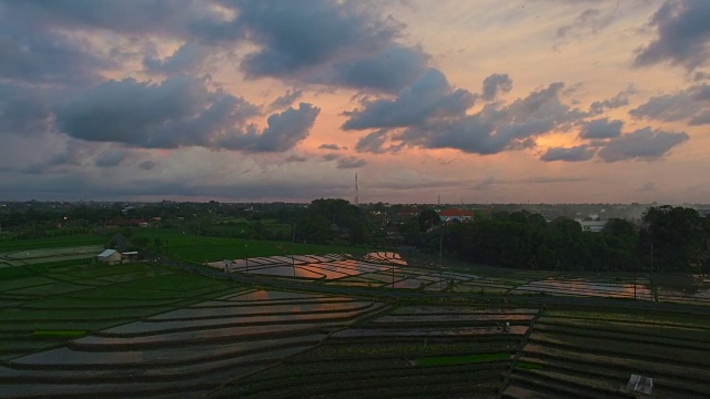 印度尼西亚巴厘岛沧古，日落时分稻田和乡村道路的彩色航拍镜头视频素材