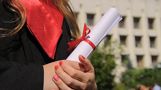 女人穿着毕业礼服，拿着文凭，望着幸福的未来视频下载