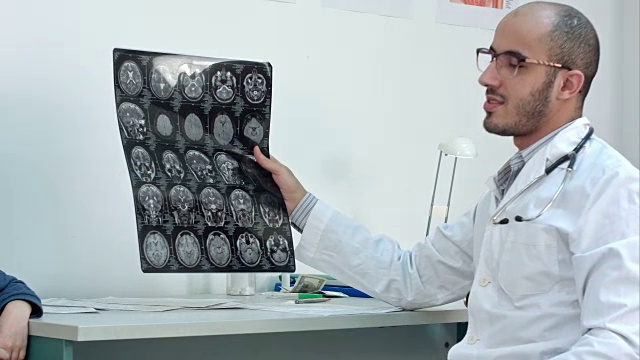 微笑的医生向他的病人展示大脑计算机断层扫描x光图像视频素材