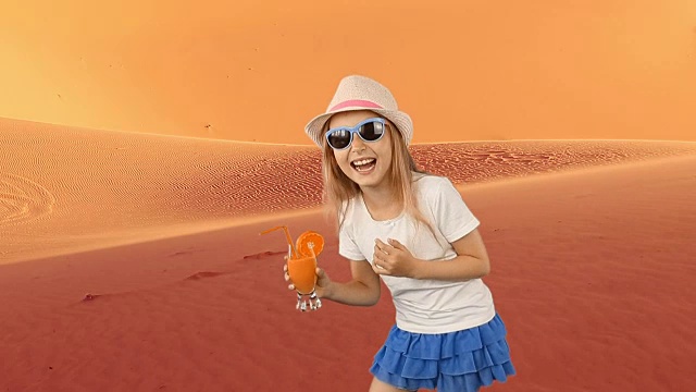 年轻的白人女孩喝橙汁。年轻女孩在撒哈拉沙漠感到口渴。沙漠气候非常炎热。夏天，在帽子里走着喝着新鲜的橙汁。视频素材