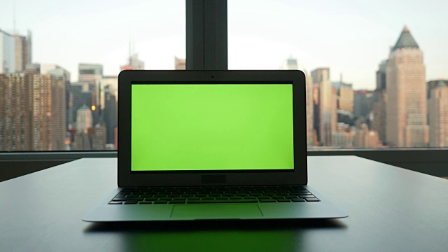 以城市景观为背景的现代办公大楼的绿屏电脑。视频素材