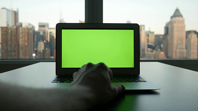 以城市景观为背景的现代办公大楼的绿屏电脑。视频素材