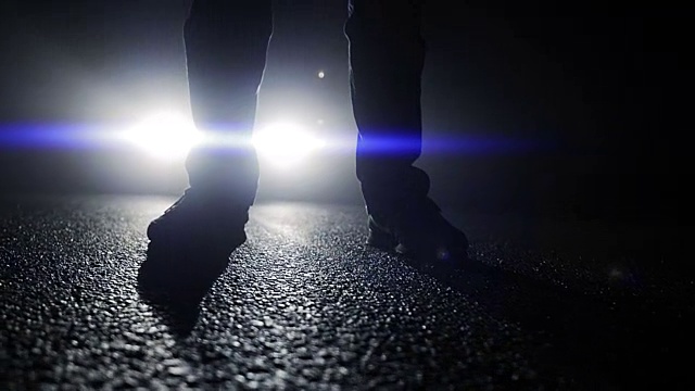 黑暗中一个人站在汽车前的轮廓。有阴影和背光的夜晚。视频素材