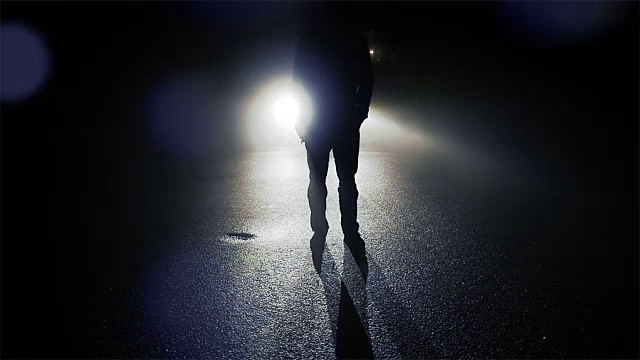黑暗中一个人站在汽车前的轮廓。有阴影和背光的夜晚。视频下载