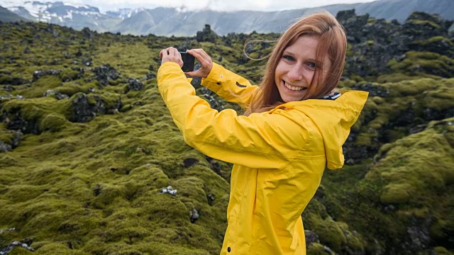 年轻的女游客拍摄冰岛的苔藓景观视频素材