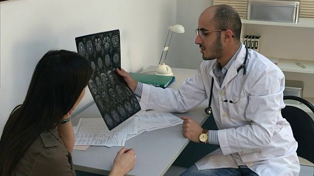 男医生向女病人展示脑部电脑断层扫描，并填写表格视频素材