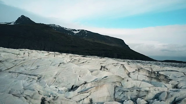 空中拍摄的带有黑色火山灰的冰缝。一架直升机飞过冰岛的Vatnajokull冰川视频素材