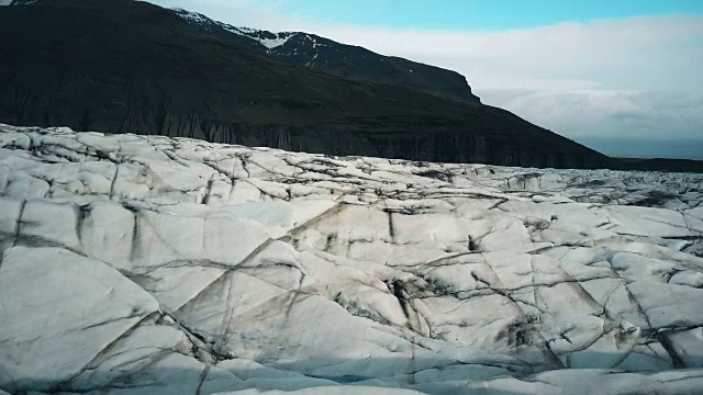 从空中俯瞰Vatnajokull冰川和黑色火山灰。一架直升机飞过冰岛的冰山视频素材
