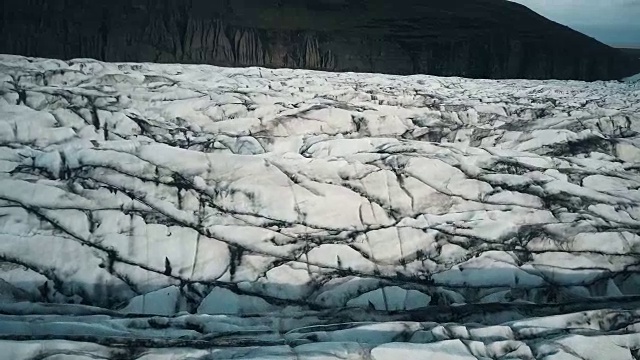 Vatnajokull冰川的近距离鸟瞰图与黑色的灰烬。无人机飞过冰岛的大冰山视频素材