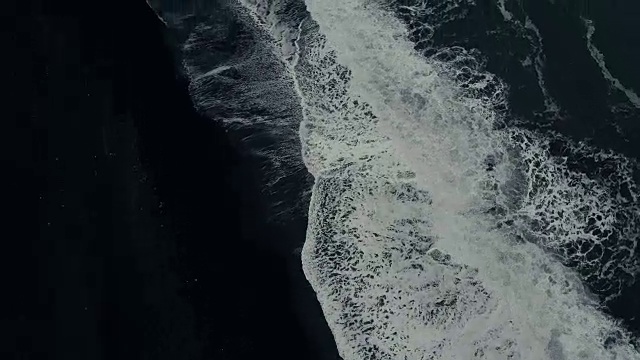 鸟瞰图的强大的波浪与泡沫来海岸上的黑色火山海滩在冰岛视频素材