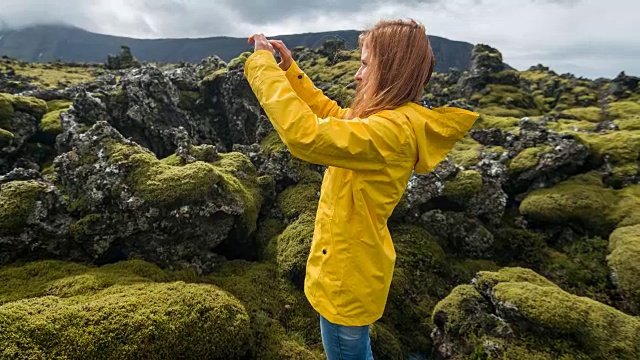 一名女子正在拍摄覆盖着苔藓的熔岩石视频素材