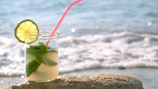 近距离的莫吉托酒精鸡尾酒站在沙滩上的沙子视频素材