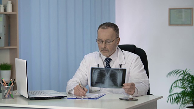 术前检查并描述病人肺部x线扫描的肺科医生视频下载