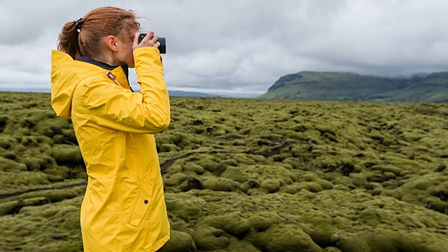 一名女子用相机拍摄冰岛覆盖着苔藓的熔岩地视频素材