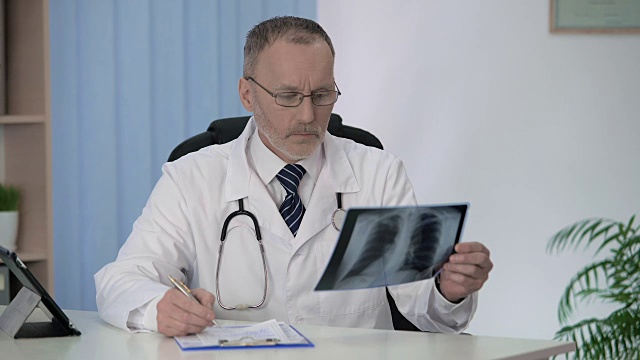 全科医生检查x光片，填写住院医疗表格视频素材
