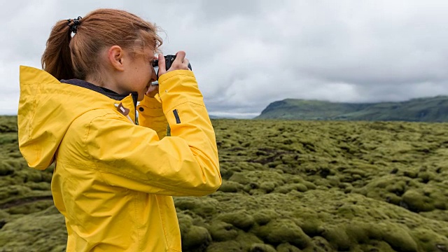 身穿黄色雨衣的游客在冰岛拍摄绿色和苔藓景观视频素材