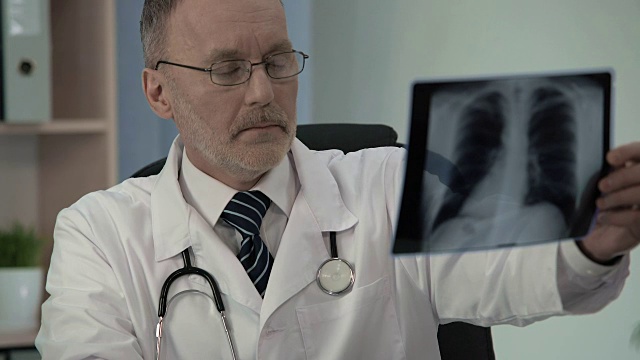 男性肺科医生仔细检查胸部x光片，寻找病理视频素材