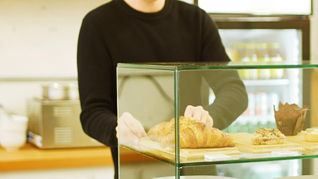 在咖啡店的陈列柜里放着一托盘牛角面包的人视频下载