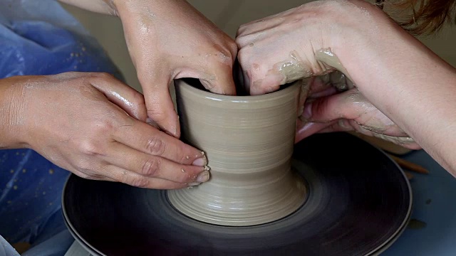 两个人的双手创造出锅，陶工的车轮。教学陶器视频素材