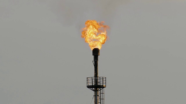 在灰色天空的映衬下，炼油厂里燃烧着的火炬视频素材