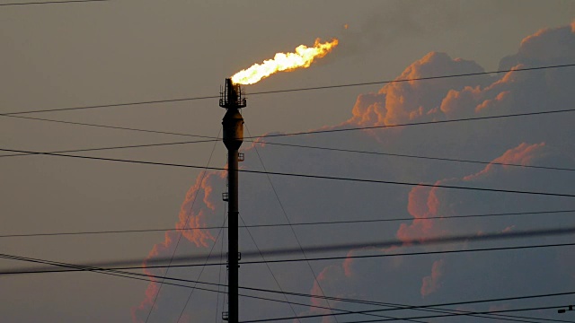 在多云的天空下，燃烧的火炬在炼油厂视频素材