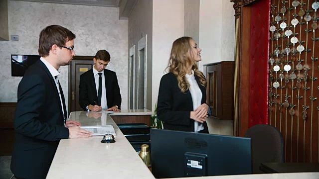 去酒店登记入住。商人们在宾馆的接待处拿着证件视频素材