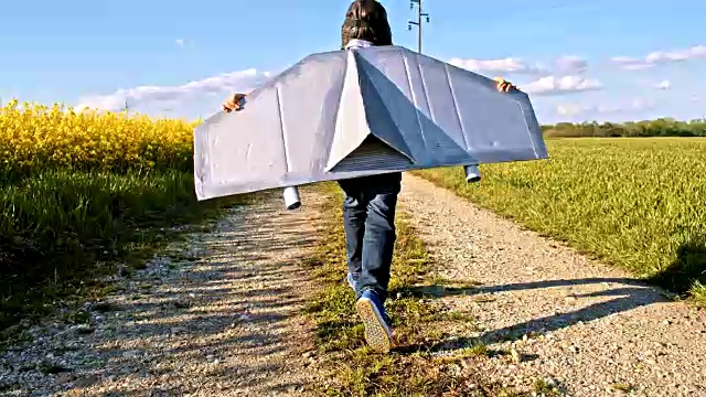 SLO MO小男孩穿着喷气背包服装在一条土路上奔跑视频素材