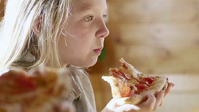 年轻的女孩吃着一片披萨视频素材