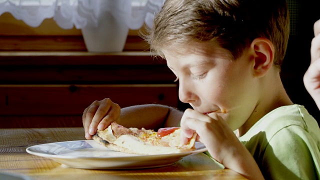 小男孩吃着一片披萨视频素材