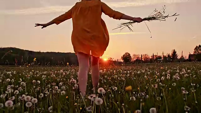 一个女人拿着一束野花跑过草地视频素材