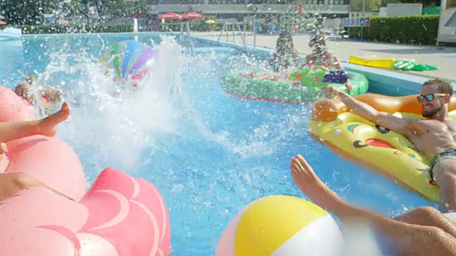 慢镜头:快乐的年轻人在五颜六色的浮子上戏水视频素材