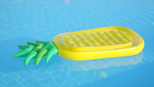 特写:空的充气菠萝漂浮在游泳池的水视频素材