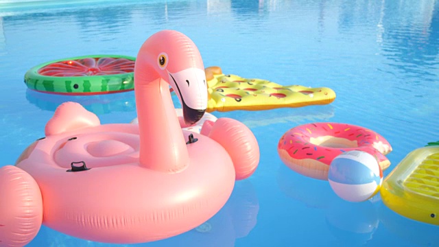 空的火烈鸟，甜甜圈，菠萝和西瓜漂浮在游泳池视频素材