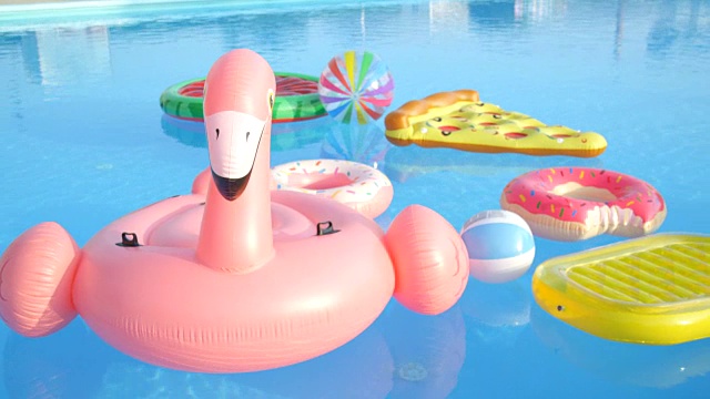 空的火烈鸟，甜甜圈，菠萝和西瓜漂浮在游泳池视频素材
