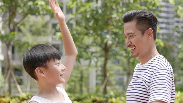亚洲父亲和儿子欢呼得分在户外篮球运动在早上视频下载