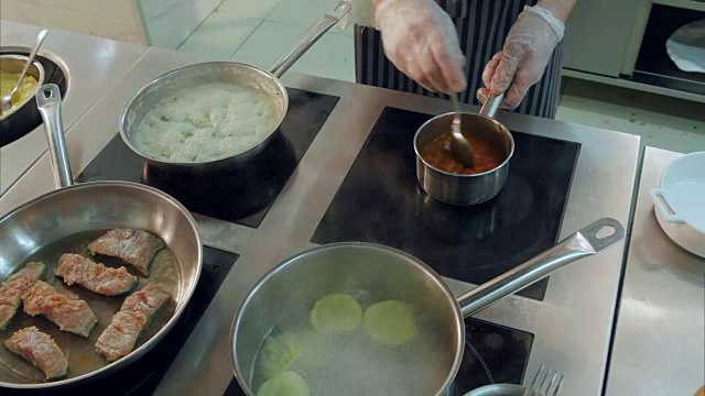 忙碌的厨师在专业厨房的灶台上烹饪不同的菜肴视频素材