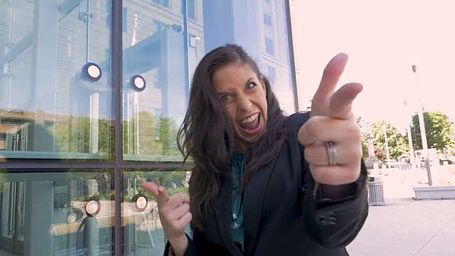 一个疯狂的女商业主管跳着胜利的舞蹈，指着别人视频下载