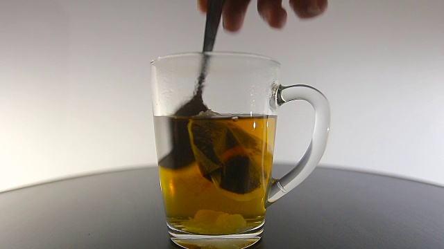 男人用勺子在玻璃杯里搅拌茶视频素材